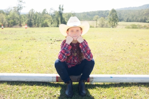Young girl in a cowboy hat sitting on a log - Australian Stock Image