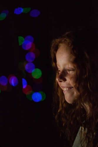 Young girl in low light with coloured lights - Australian Stock Image