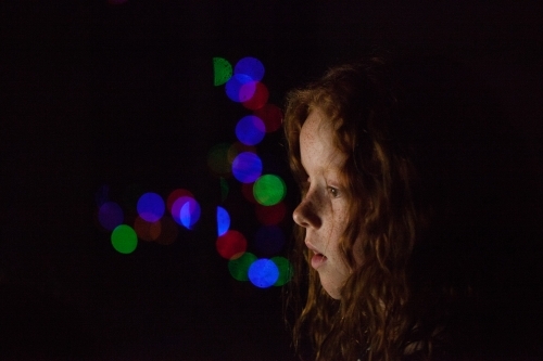 Young girl in low light with coloured lights - Australian Stock Image