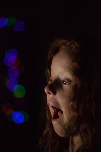 Young girl in low light with coloured lights - Australian Stock Image