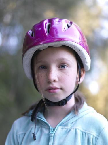 Young girl in purple helmet preparing to go bike riding - Australian Stock Image