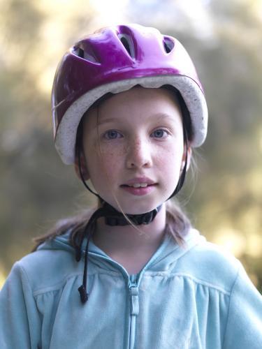 Young girl in purple helmet preparing to go bike riding - Australian Stock Image