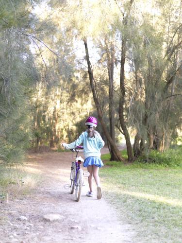 Young girl in purple helmet preparing to go bike riding - Australian Stock Image