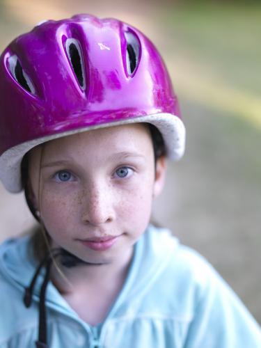 Young girl in purple helmet preparing to go bike riding - Australian Stock Image