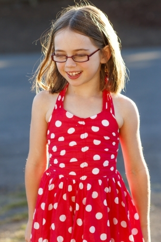 Young girl in red polka dot dress backlit by sun - Australian Stock Image
