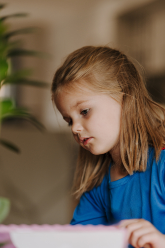 Young girl in superhero costume making an artwork. - Australian Stock Image