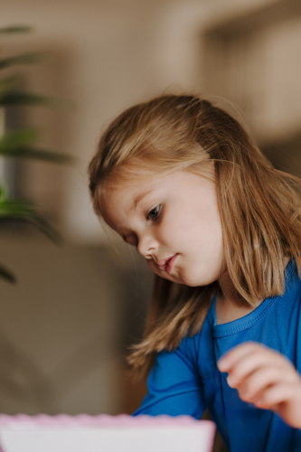 Young girl in superhero costume making an artwork. - Australian Stock Image