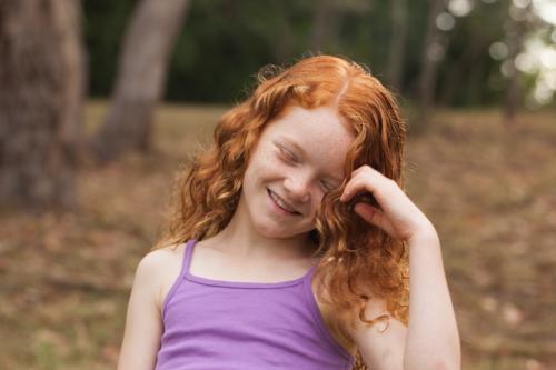 Young girl laughing in an open field - Australian Stock Image