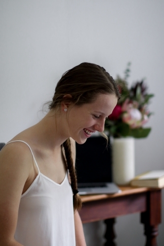 Young girl laughing inside in front of work desk - Australian Stock Image