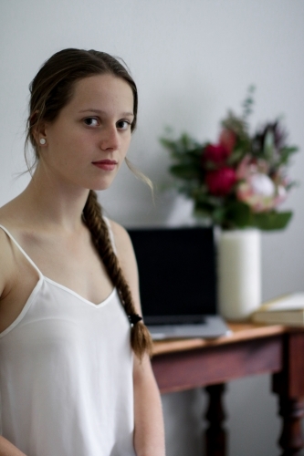 Young girl looking at camera inside in front of desk - Australian Stock Image