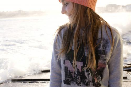 Young girl looking over her shoulder with beach behind her - Australian Stock Image