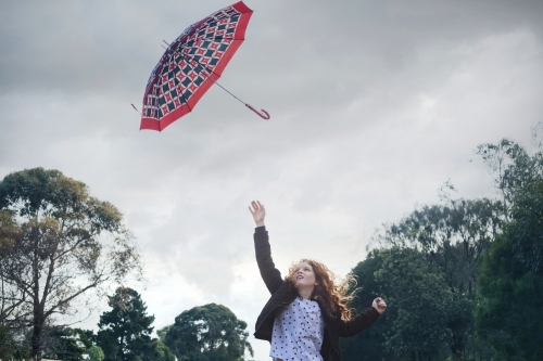 Young girl losing her umbrella on a windy winter day