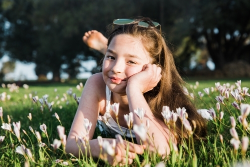 Young girl lying in a flower field smiling at camera
