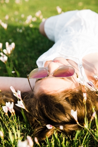 Young girl lying on her back in field of flowers - Australian Stock Image