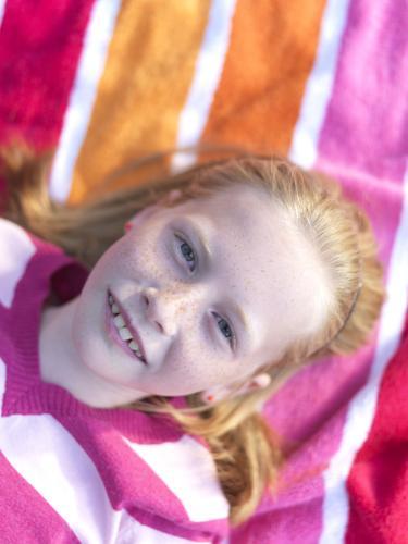 Young girl lying on stripy towel