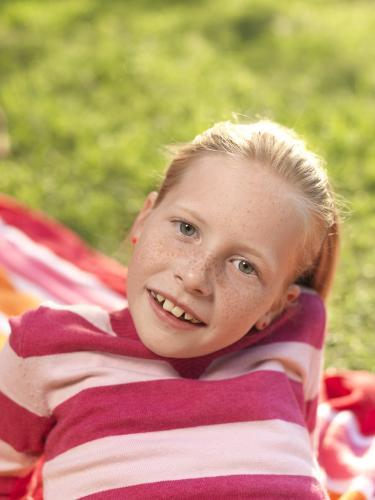 Young girl lying on stripy towel - Australian Stock Image