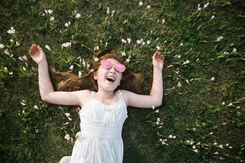 Young girl lying on the grass, laughing - Australian Stock Image