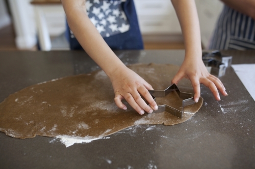 Young girl making gingerbread biscuits at home - Australian Stock Image