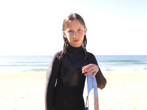 Young girl on beach in wetsuit with body board - Australian Stock Image