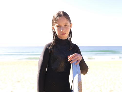 Young girl on beach in wetsuit with body board