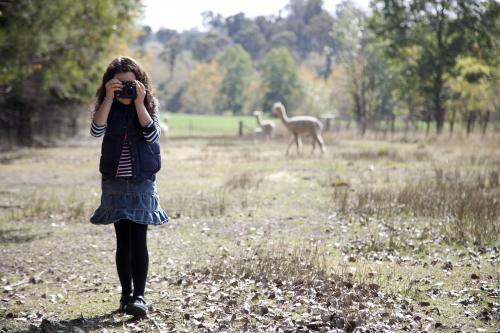 Young girl outside on a farm using a digital camera