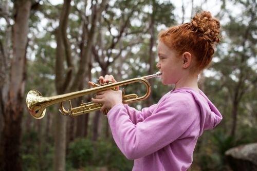 Young girl playing a trumpet outside - Australian Stock Image