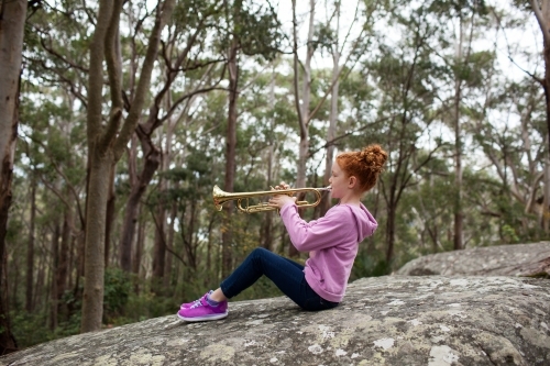 Young girl playing a trumpet outside