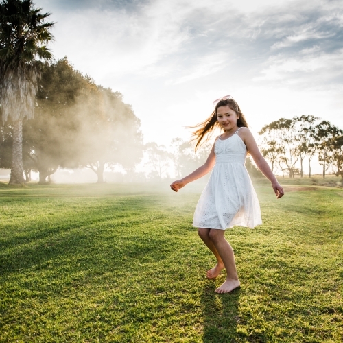 Young girl playing in a field in the sunshine - Australian Stock Image