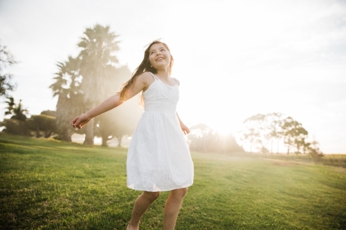 Young girl playing in a field in the sunshine - Australian Stock Image