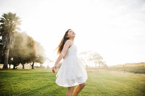 Young girl playing in a field in the sunshine - Australian Stock Image