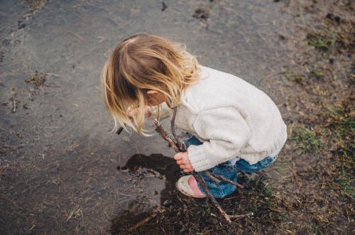 Young girl playing in puddle