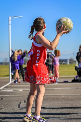 Young girl playing netball passing a ball - Australian Stock Image