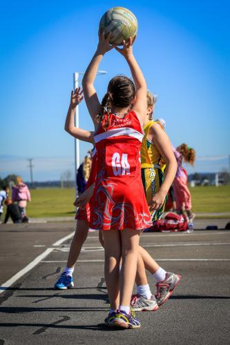 Young girl playing netball shooting for goal - Australian Stock Image