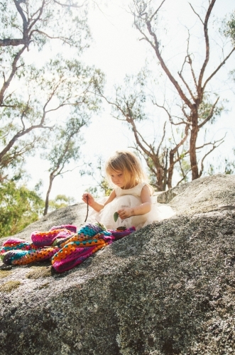 Young girl playing on a huge boulder