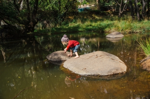 Young girl playing on rocks in a creek
