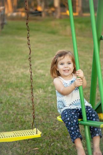 Young girl playing on the swings in the backyard - Australian Stock Image