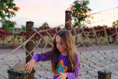 Young girl playing with sand at dusk - Australian Stock Image