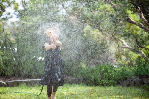 Young girl playing with sprinkler in summer