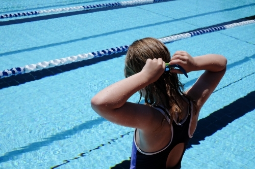 Young girl putting her goggles on for swimming