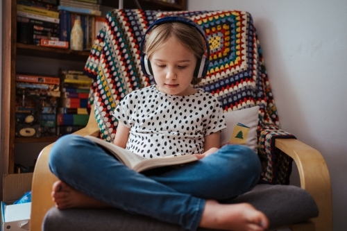 Young girl reading a book at home - Australian Stock Image