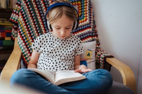 Young girl reading a book at home - Australian Stock Image
