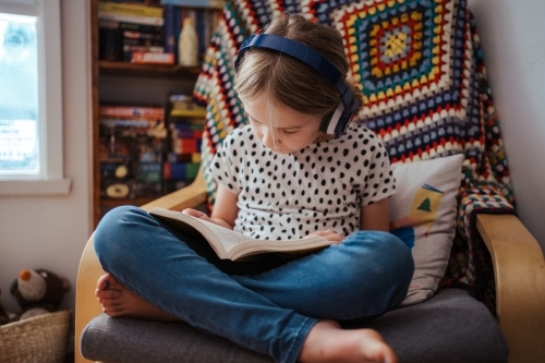Young girl reading a book at home