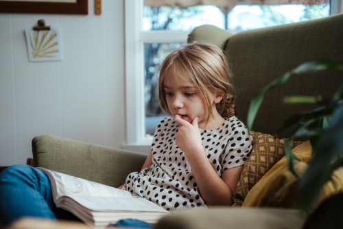 Young girl reading a book at home - Australian Stock Image