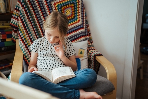 Young girl reading a book at home - Australian Stock Image