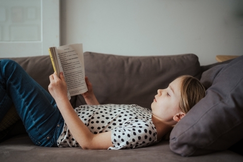 Young girl reading a book at home - Australian Stock Image