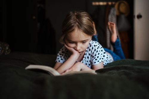 Young girl reading a book at home - Australian Stock Image