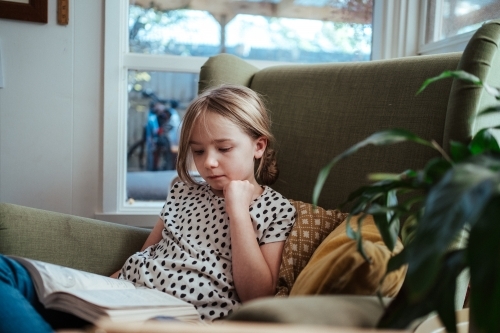 Young girl reading a book at home - Australian Stock Image