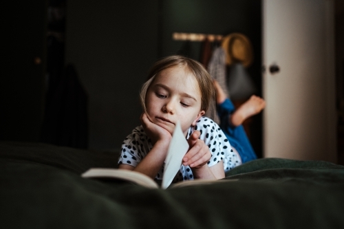 Young girl reading a book at home - Australian Stock Image
