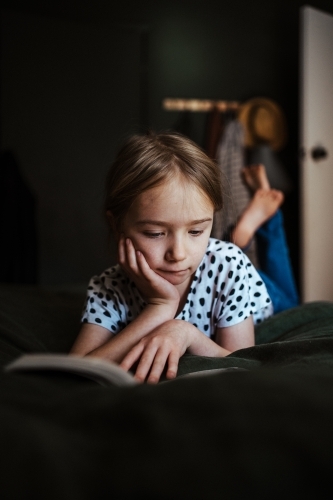 Young girl reading a book at home - Australian Stock Image