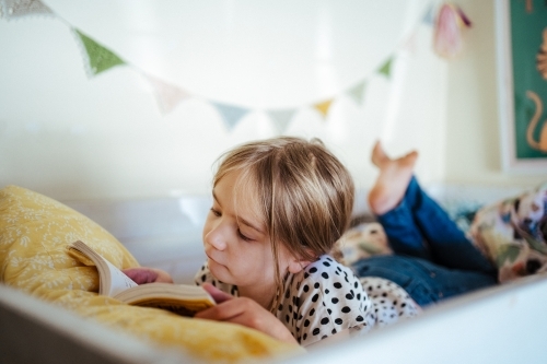 Young girl reading a book at home